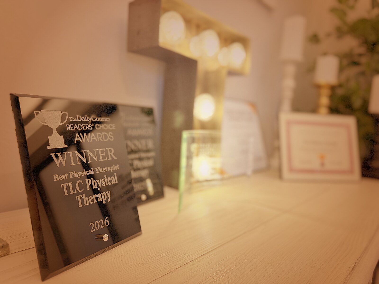 TLC Physical Therapy's award display: the 2026 Daily Courier Readers' Choice Winner plaque for Best Physical Therapist in front, with more plaques and certificates behind it